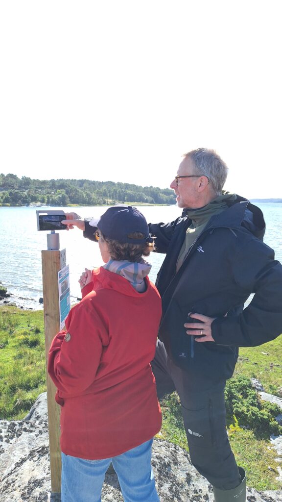 Två personer står på en strand och tittar på ett stativ.